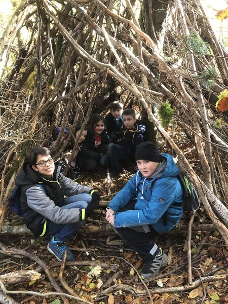 Bild von Kindern in einem Zelt aus Holz im Wald.